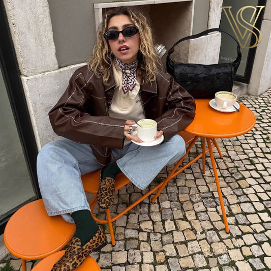Distressed brown faux-leather zip-up jacket featuring a pointed collar, styled with a white crop top and blue jeans for a classic vstyles urban look.