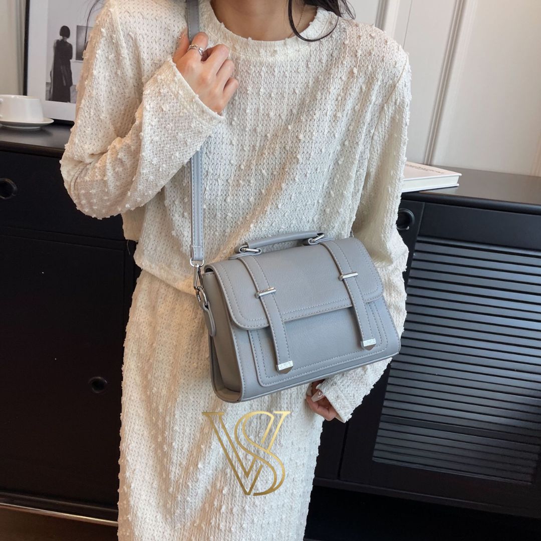 Sophisticated grey crossbody satchel featuring a top handle and silver metal hardware.