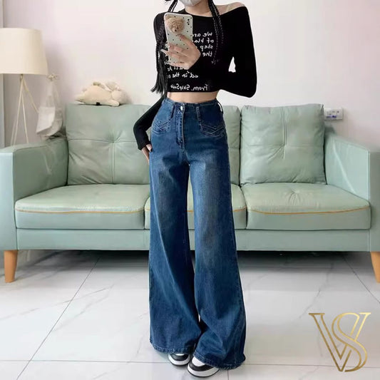 High-waisted medium blue wide-leg jeans with decorative front pocket stitching and a relaxed silhouette, styled with a black long-sleeve crop top for the vstyles collection.