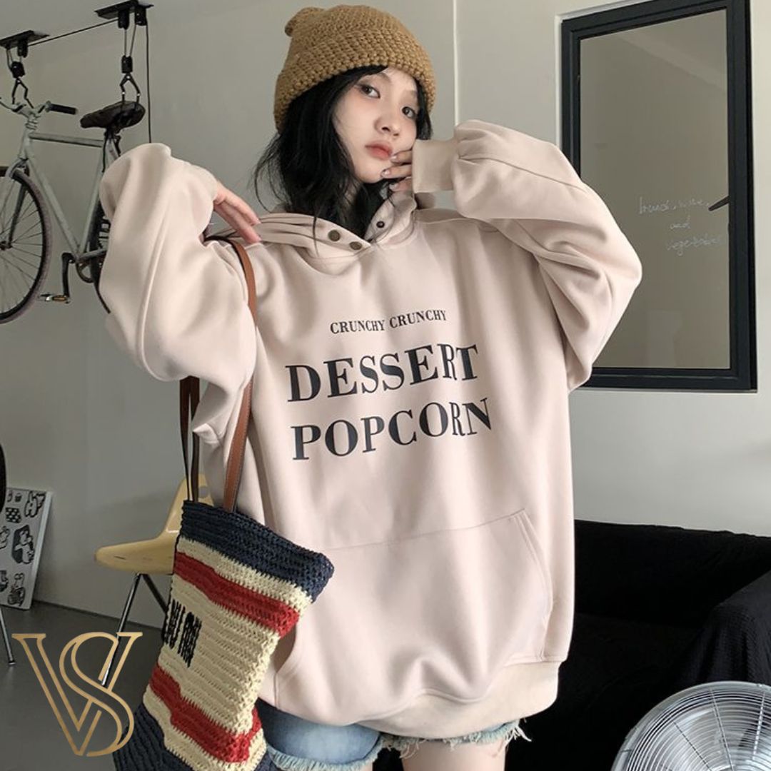 Oversized light pinkish-beige hoodie featuring "CRUNCHY CRUNCHY DESSERT POPCORN" graphic text and a front pouch pocket for the vstyles collection.