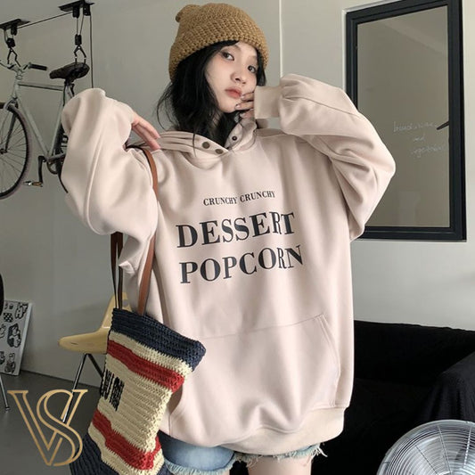 Oversized light pinkish-beige hoodie featuring "CRUNCHY CRUNCHY DESSERT POPCORN" graphic text and a front pouch pocket for the vstyles collection.