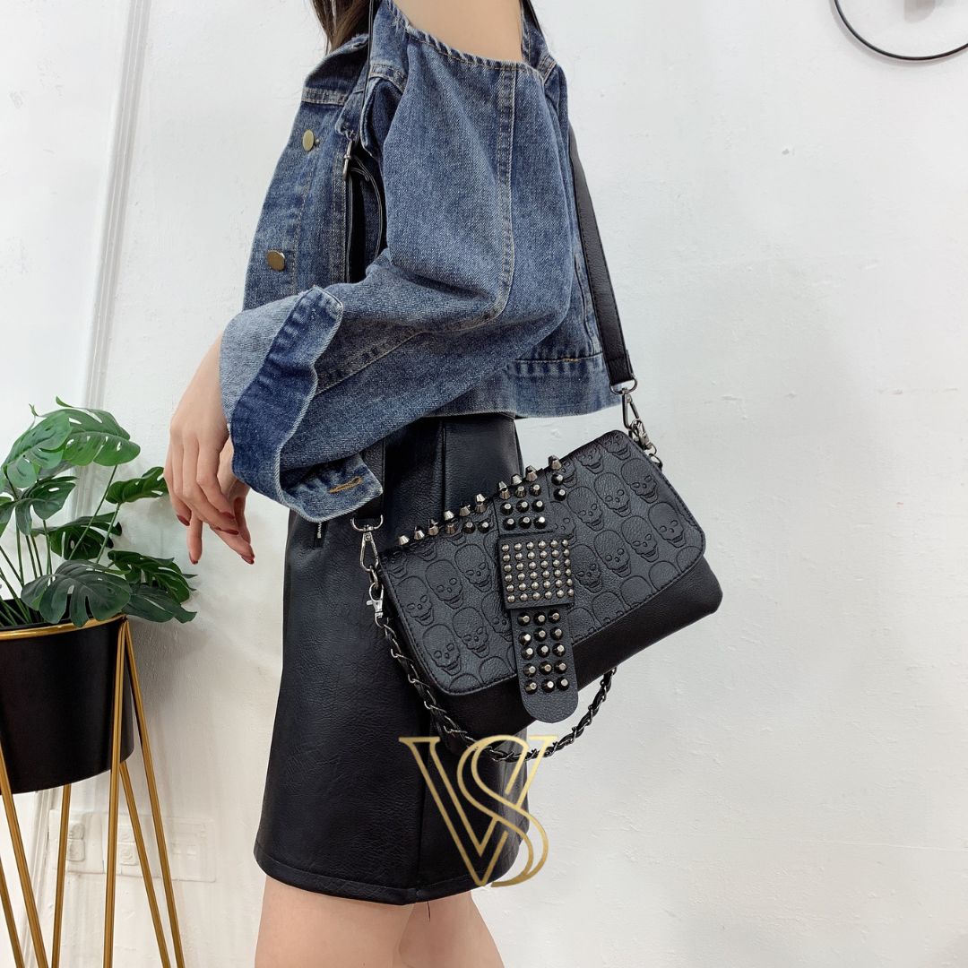 Black embossed skull crossbody bag with edgy silver studded detailing on the flap and adjustable shoulder strap.