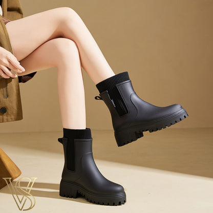 Black waterproof ankle boot with a chunky lug sole and matching black ribbed knit sock-style collar.