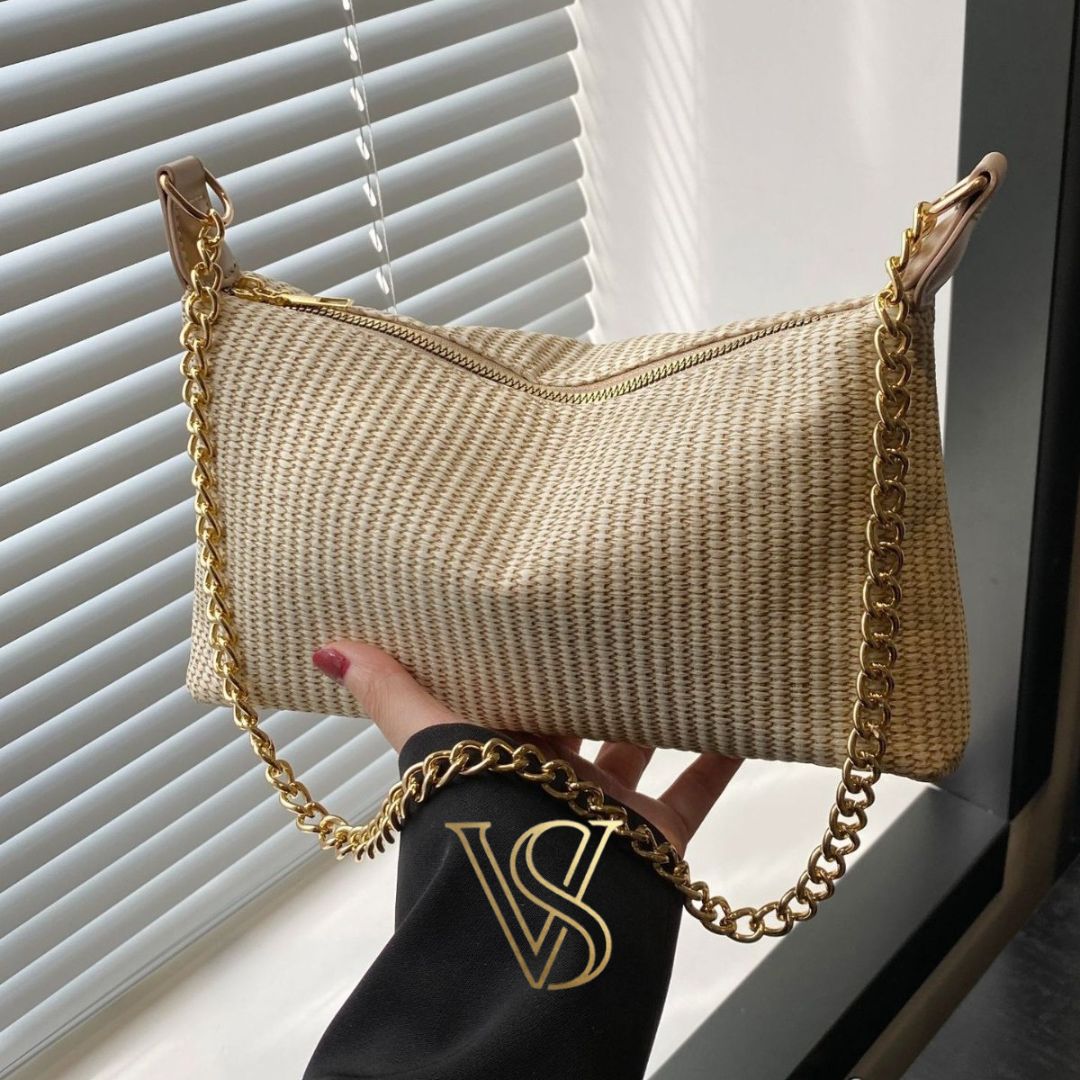 Cream woven straw shoulder bag with a gold chain strap and top zipper closure.