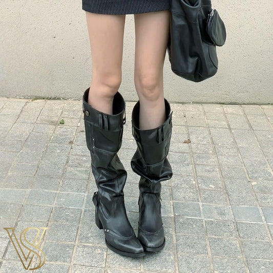 Edgy black slouchy knee-high boots featuring a pointed toe, chunky mid-heel, and metallic stud accents.