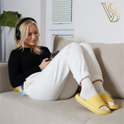 Lifestyle shot of a woman relaxing on a couch wearing bright yellow platform cloud slides with white socks, showcasing a cozy and trendy look for vstyles.