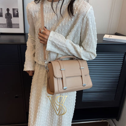 Chic beige crossbody satchel featuring a top handle and silver buckle accents.