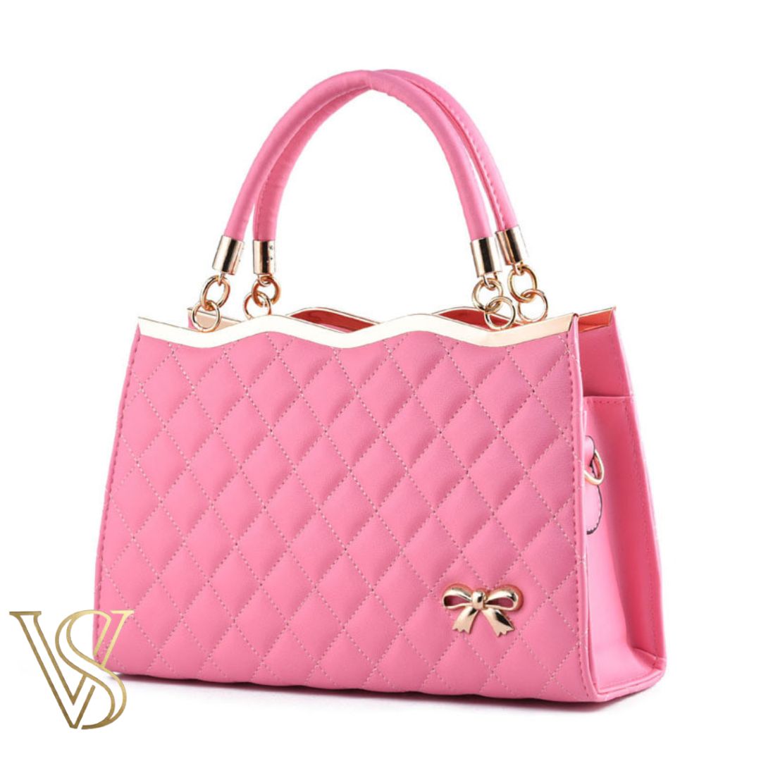 Charming light pink quilted handbag with a wavy gold top border, top handles, and a delicate gold bow charm.