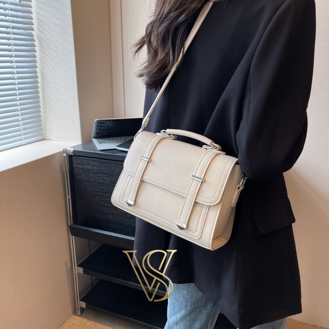 Minimalist cream-colored crossbody bag with a structured silhouette and silver metal details
