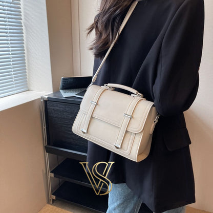 Minimalist cream-colored crossbody bag with a structured silhouette and silver metal details