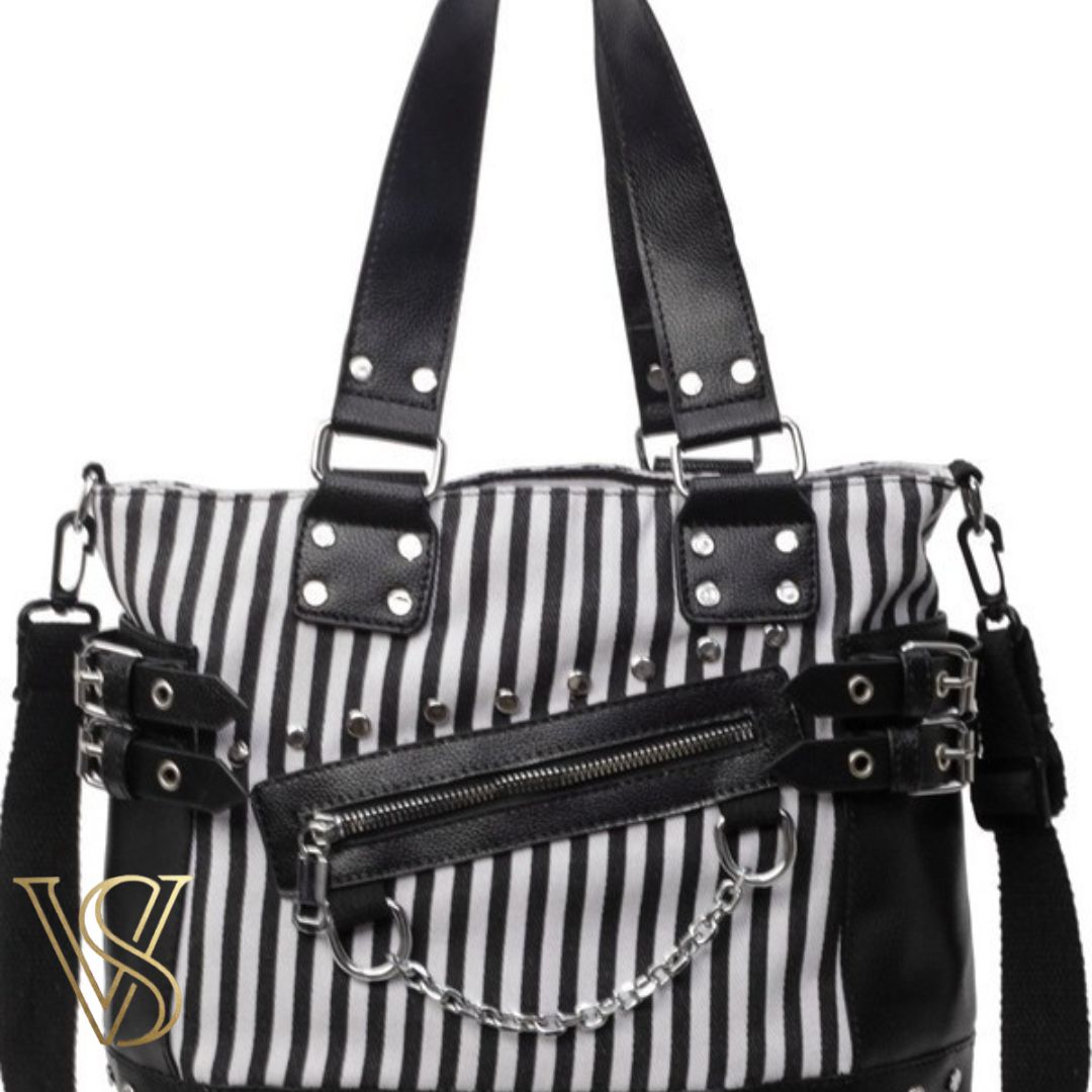 Punk-inspired tote bag with black and white vertical stripes, detailed with silver studs, side buckles, and a hanging metal chain.