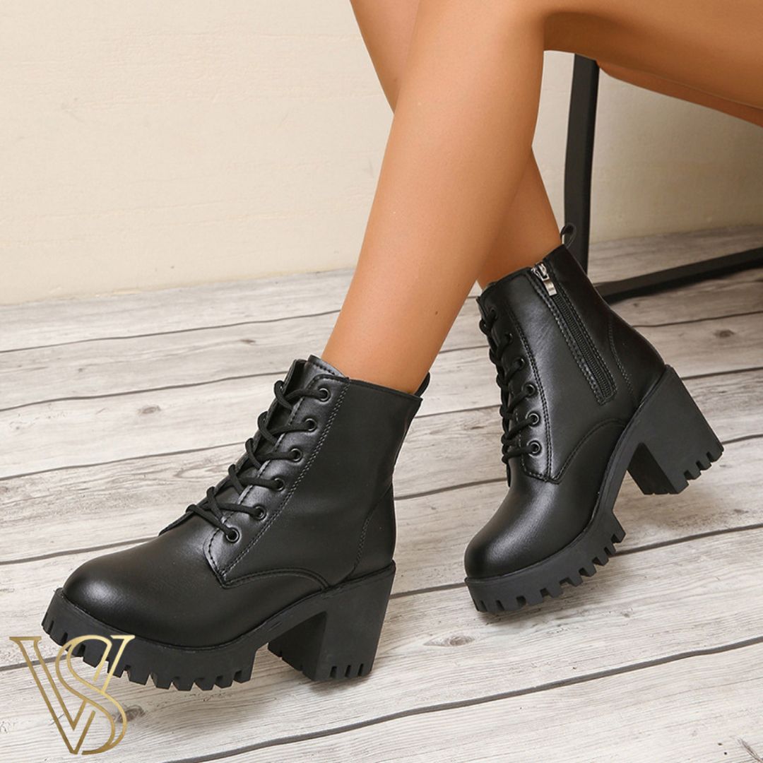 Black lace-up combat boots with a high chunky block heel, rugged lug sole, and functional side zipper.