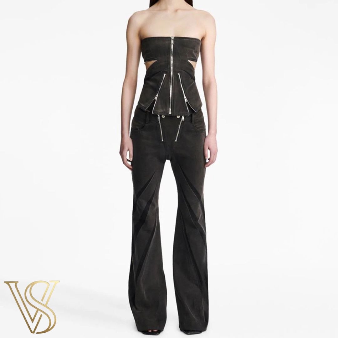Bold washed black denim ensemble with a strapless zippered cutout top and flared trousers featuring sleek dark contrast inserts.