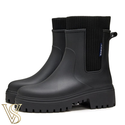 Black waterproof ankle boot with a chunky lug sole and matching black ribbed knit sock-style collar.