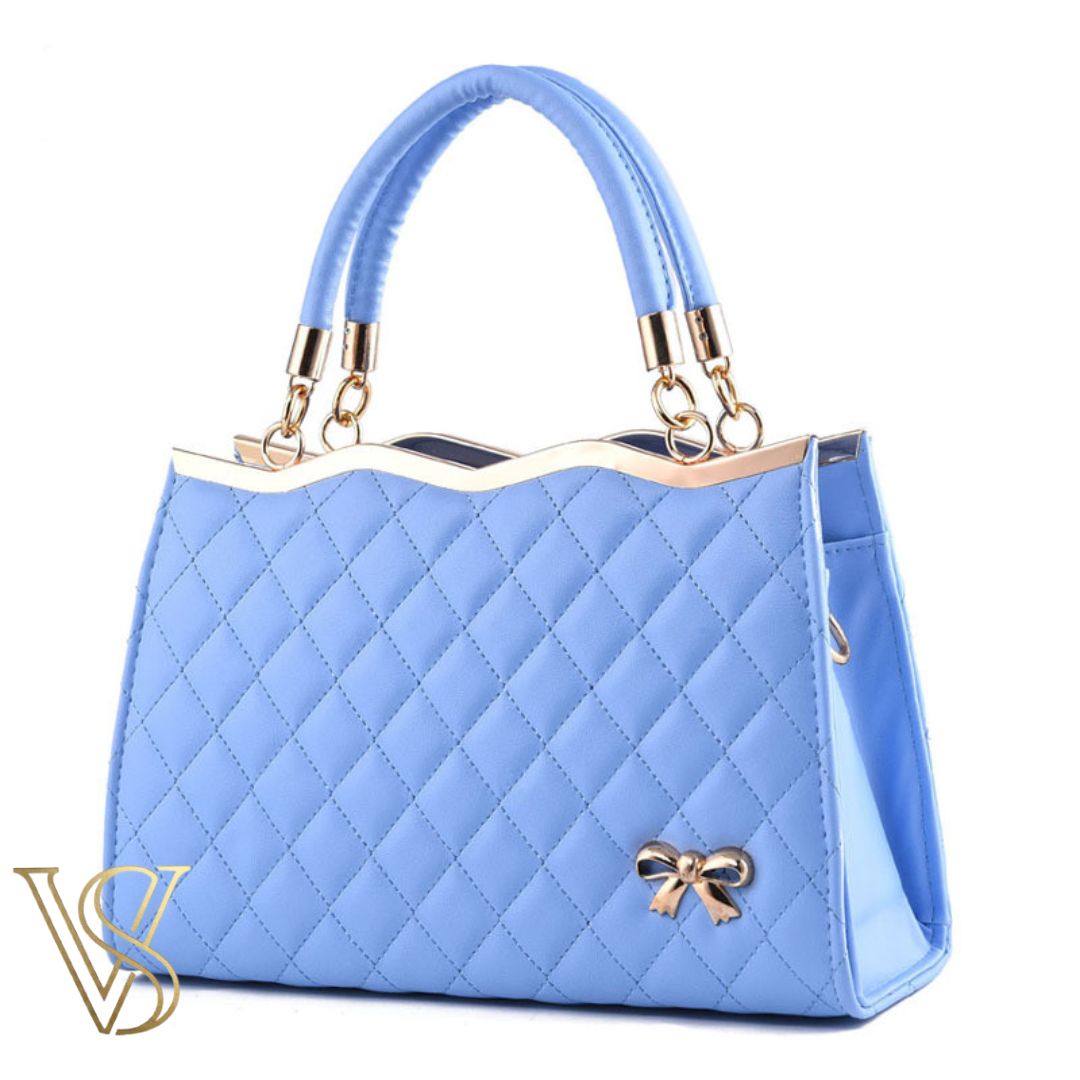 Pretty sky blue quilted handbag featuring a scalloped gold top, top handles, and a decorative gold bow charm.
