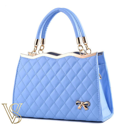 Pretty sky blue quilted handbag featuring a scalloped gold top, top handles, and a decorative gold bow charm.
