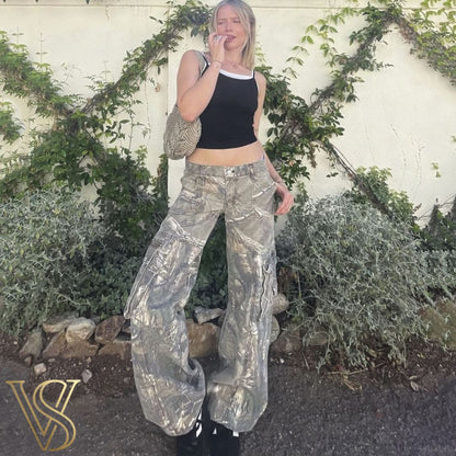 Low-rise baggy cargo trousers featuring a forest camouflage pattern and side utility pockets, paired with a black tank top by vstyles.